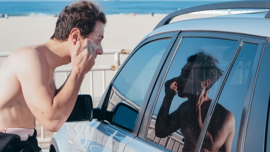 Personne appliquant de la crème solaire sur son bras à la plage