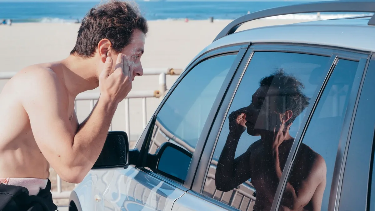 Personne appliquant de la crème solaire sur son bras à la plage