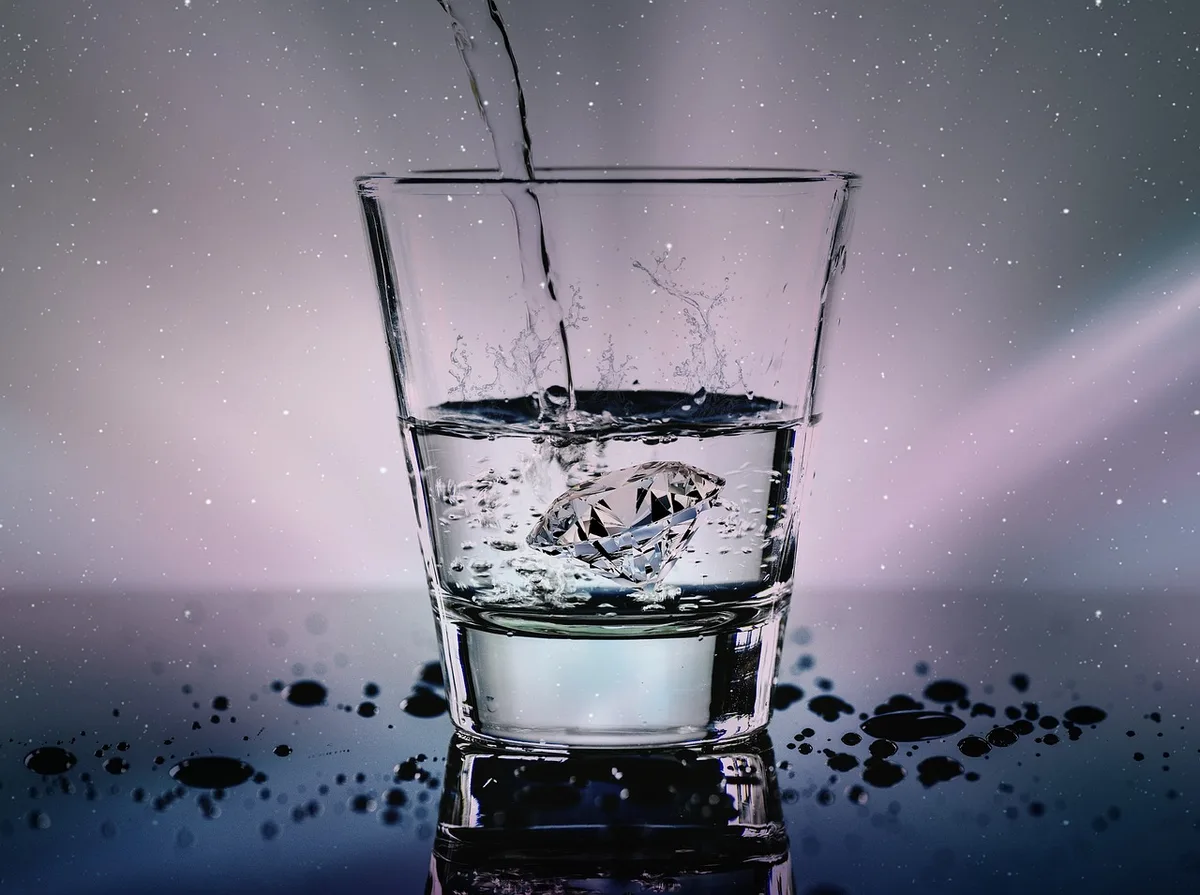 Femme buvant un grand verre d'eau près d'une fenêtre en journée