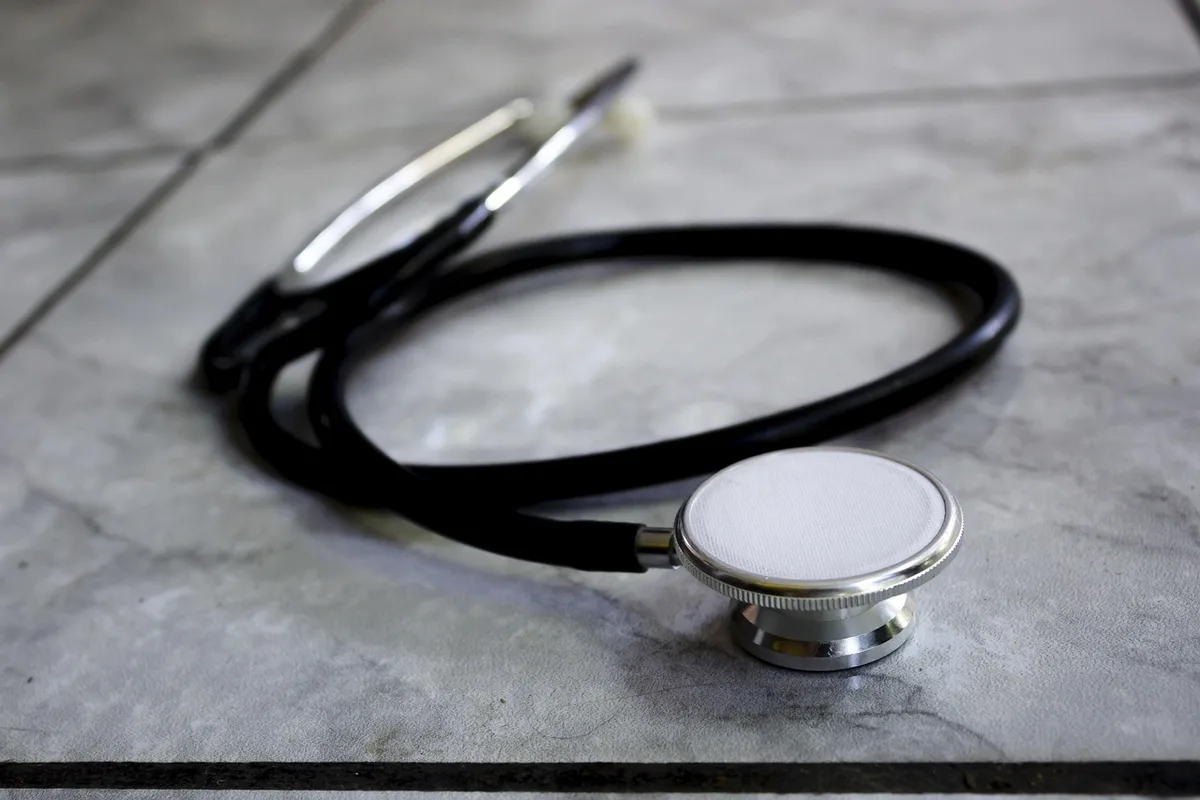 Personne remplissant un bilan de santé à domicile avec un thermomètre et des documents