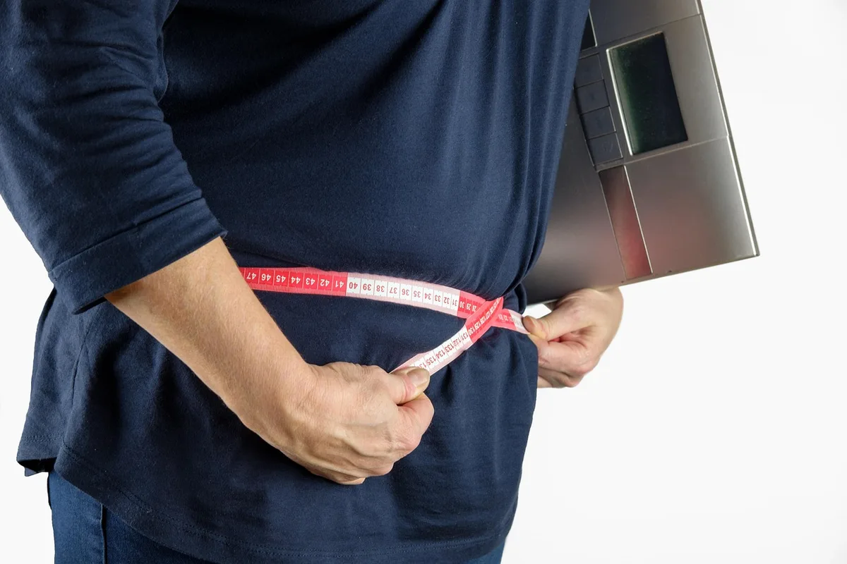 Balance et mains pesant une personne, montre la différence poids vs composition corporelle
