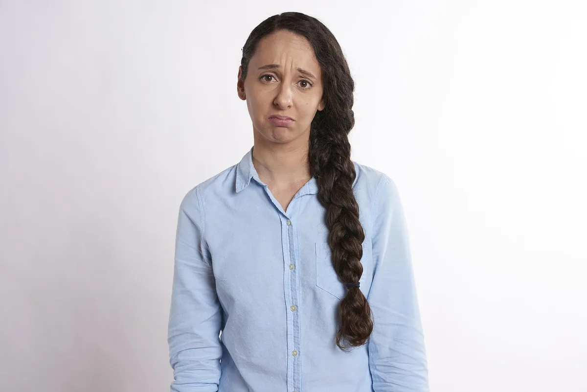 Femme assise à une table la main sur le front, signes de fatigue et stress